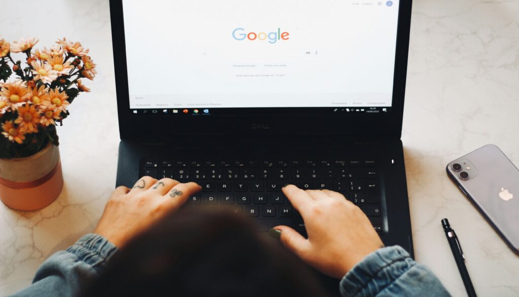 ujęcie z góry na osobę siedzącą przed laptopem z otwartą stroną Google