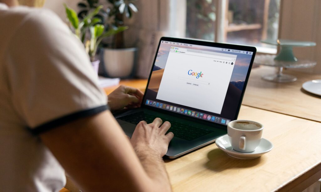 mężczyzna siedzący przed laptopem z otwartą stroną wyszukiwarki Google